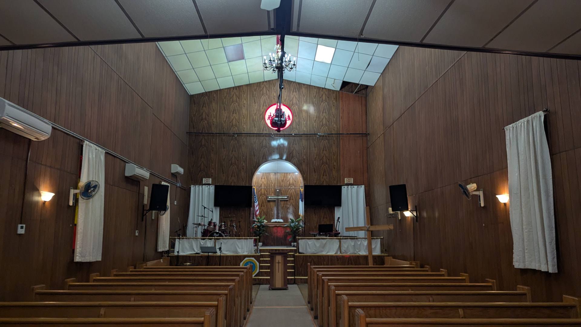 Interior of Monte Sion Church in the East Village, New York, with wood-panelled walls, pews and wall-mounted mini-split units